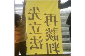 民主鬥陣成員困在房間，透過窗戶向外貼海報。（圖／翻攝民主鬥陣臉書）