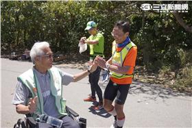 漸凍人協會林詠沂理事與抵達終點的超馬跑者擊掌致意