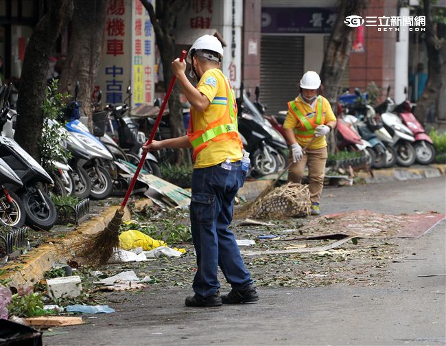 「梅姬」強風豪雨後帶來滿街落葉，清潔人員辛苦地清理。（記者邱榮吉/攝影）