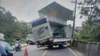 貨櫃車「蚌殼精」　車門撞破路邊圍牆