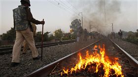 印度警察走過一個國家立法者的燃燒肖像在鐵路軌道在印度博帕爾，星期六，2011年12月3日。世界上最糟糕的工業事故的數千名倖存者阻止列車通過印度中部城市星期六要求更多補償。抗議是在博帕爾的災難27週年，在那裡一個聯合碳化物農藥廠洩漏致命的氣體，殺死了大約15,000人，致殘數万以上。/(圖／美聯社／達志影像)