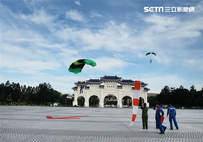 陸軍「神龍小組高空跳傘」在自由廣場前展現「翱翔天際現神龍｣由空訓中心派出8名神龍小組成員，攜帶國旗、三軍軍旗、彩帶、煙幕，區分兩波次實施，每波次各4員，執行4,500英呎高空疊傘「扇形、踩肩」及定點跳傘等操演任務。（記者邱榮吉/攝影）