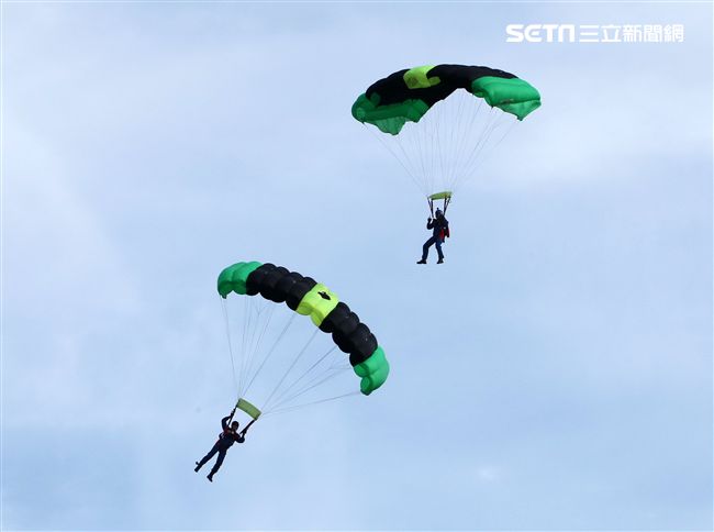 陸軍「神龍小組高空跳傘」在自由廣場前展現「翱翔天際現神龍｣由空訓中心派出8名神龍小組成員，攜帶國旗、三軍軍旗、彩帶、煙幕，區分兩波次實施，每波次各4員，執行4,500英呎高空疊傘「扇形、踩肩」及定點跳傘等操演任務。（記者邱榮吉/攝影）