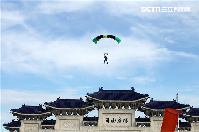 陸軍「神龍小組高空跳傘」在自由廣場前展現「翱翔天際現神龍｣由空訓中心派出8名神龍小組成員，攜帶國旗、三軍軍旗、彩帶、煙幕，區分兩波次實施，每波次各4員，執行4,500英呎高空疊傘「扇形、踩肩」及定點跳傘等操演任務。（記者邱榮吉/攝影）