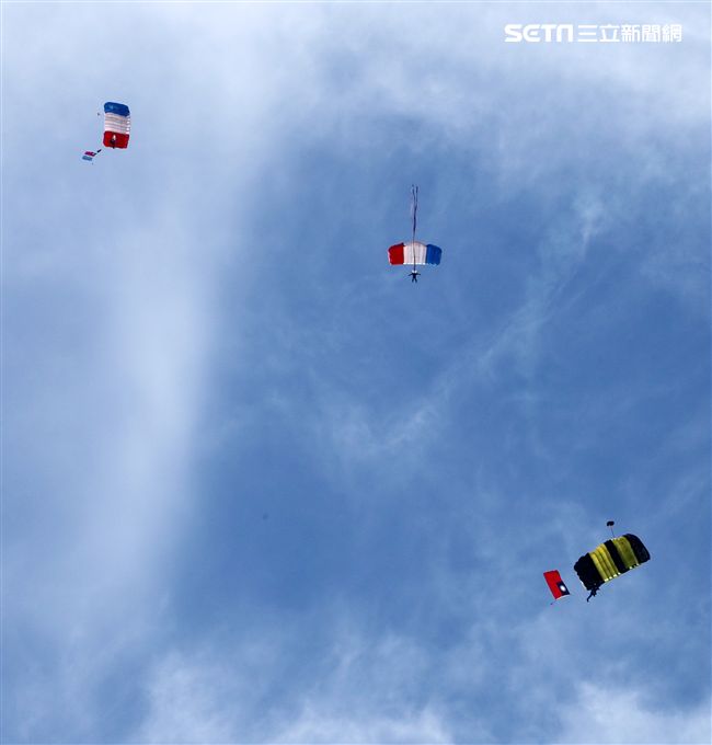 陸軍「神龍小組高空跳傘」在自由廣場前展現「翱翔天際現神龍｣由空訓中心派出8名神龍小組成員，攜帶國旗、三軍軍旗、彩帶、煙幕，區分兩波次實施，每波次各4員，執行4,500英呎高空疊傘「扇形、踩肩」及定點跳傘等操演任務。（記者邱榮吉/攝影）