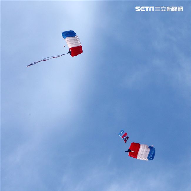 陸軍「神龍小組高空跳傘」在自由廣場前展現「翱翔天際現神龍｣由空訓中心派出8名神龍小組成員，攜帶國旗、三軍軍旗、彩帶、煙幕，區分兩波次實施，每波次各4員，執行4,500英呎高空疊傘「扇形、踩肩」及定點跳傘等操演任務。（記者邱榮吉/攝影）