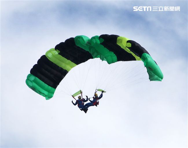 陸軍「神龍小組高空跳傘」在自由廣場前展現「翱翔天際現神龍｣由空訓中心派出8名神龍小組成員，攜帶國旗、三軍軍旗、彩帶、煙幕，區分兩波次實施，每波次各4員，執行4,500英呎高空疊傘「扇形、踩肩」及定點跳傘等操演任務。（記者邱榮吉/攝影）