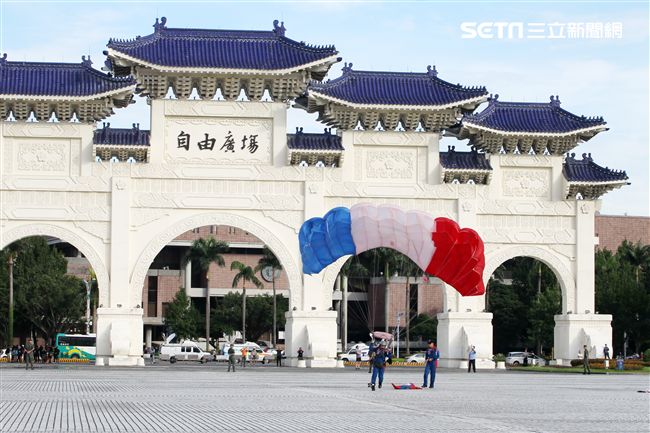 陸軍「神龍小組高空跳傘」在自由廣場前展現「翱翔天際現神龍｣由空訓中心派出8名神龍小組成員，攜帶國旗、三軍軍旗、彩帶、煙幕，區分兩波次實施，每波次各4員，執行4,500英呎高空疊傘「扇形、踩肩」及定點跳傘等操演任務。（記者邱榮吉/攝影）