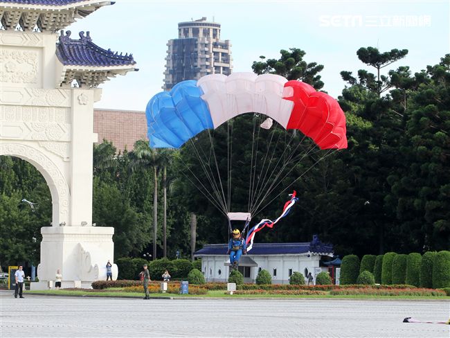 陸軍「神龍小組高空跳傘」在自由廣場前展現「翱翔天際現神龍｣由空訓中心派出8名神龍小組成員，攜帶國旗、三軍軍旗、彩帶、煙幕，區分兩波次實施，每波次各4員，執行4,500英呎高空疊傘「扇形、踩肩」及定點跳傘等操演任務。（記者邱榮吉/攝影）