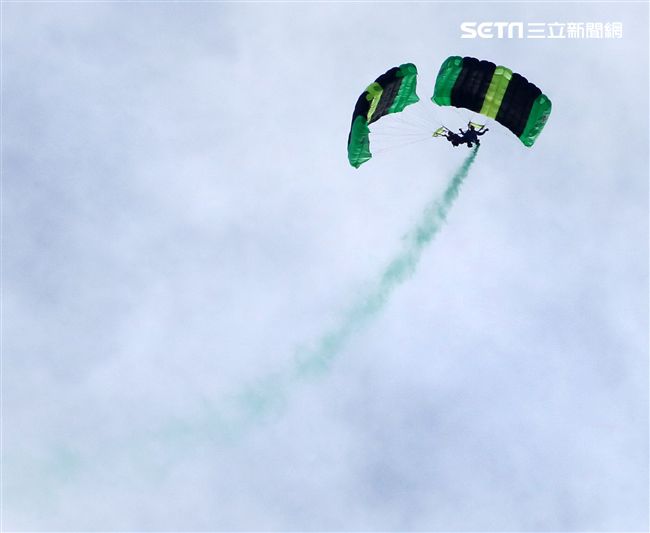 陸軍「神龍小組高空跳傘」在自由廣場前展現「翱翔天際現神龍｣由空訓中心派出8名神龍小組成員，攜帶國旗、三軍軍旗、彩帶、煙幕，區分兩波次實施，每波次各4員，執行4,500英呎高空疊傘「扇形、踩肩」及定點跳傘等操演任務。（記者邱榮吉/攝影）