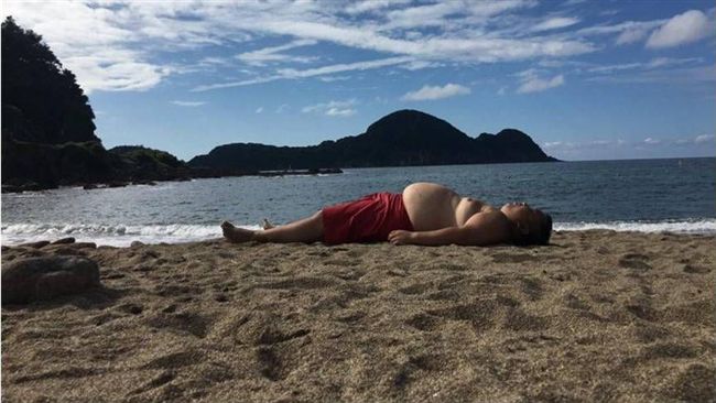 大肚男躺海灘　竟「神還原」後方山景