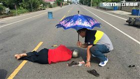 7旬老翁車禍倒地，員警撐傘替他遮陽等待救護車到場。（圖／警方提供）
