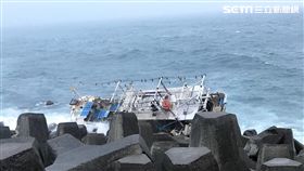 「新德溢12號」漁船出海捕螃蟹，遭海浪打上八尺門漁港防坡堤，張姓船長發射信號彈求援，岸巡及消防人員前往協助，並架設雙節梯助張男脫困。（翻攝畫面）