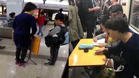 上海地鐵車廂內一名男童母親攤開摺疊桌讓兒子寫作業。（圖／翻攝澎湃新聞）