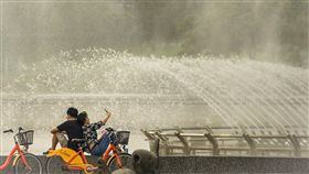 天氣晴朗穩定　民眾河濱遊憩中央氣象局表示，21日各地天氣晴朗穩定，中午西半部及東北部高溫可以達到攝氏33、34度。下午台北地區雲層漸厚，氣溫略降，民眾到河濱公園噴水池邊休憩。中央社記者裴禛攝　107年5月21日