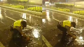 警員在雨中的大馬路上，徒手清理地下道排水孔。（圖／翻攝李孟諺臉書）