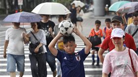 對流旺盛　13縣市大雨特報（2）午後對流發展旺盛，中央氣象局30日下午發布大雨特報，走在台北街頭的民眾撐傘遮雨，也有小朋友隨即拿起足球擋雨。中央社記者吳翊寧攝　107年6月30日