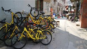 摩拜單車ofo小黃車堆疊路邊中國大陸市占率加起來逾9成的摩拜單車和ofo小黃車在歷經燒錢的終極PK後，終於傳出要合併了。圖為摩拜單車（橘色）與ofo小黃車（黃色）在上海一處社區內堆疊的照片。中央社記者陳家倫上海攝　106年10月3日