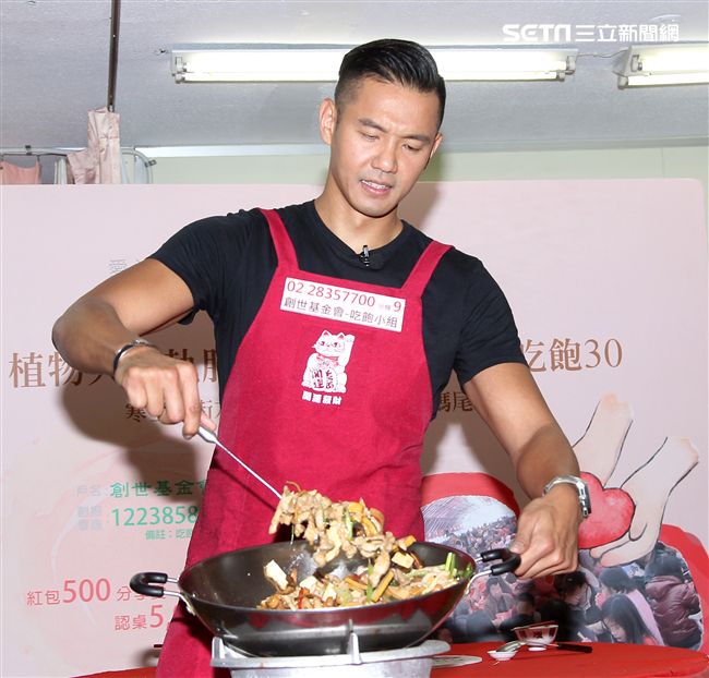 陳建州（黑人）做道地的客家小炒，提前與弱勢同桌圍爐，呼籲民眾小額捐款「搶救」尾牙宴。（記者邱榮吉/攝影）