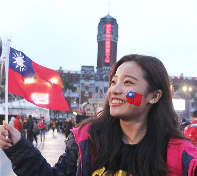 正妹臉上貼著國旗貼圖手上揮著國旗參加中華民國108年元旦升旗典禮。（記者邱榮吉/攝影）