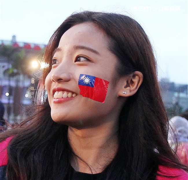 正妹臉上貼著國旗貼圖手上揮著國旗參加中華民國108年元旦升旗典禮。（記者邱榮吉/攝影）