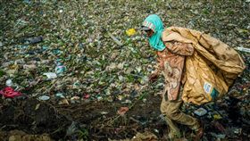 西爪哇省炙熱的陽光下，男孩們在搖搖晃晃的木製坡道上玩耍閒聊，而他們腳下正是印尼汙染最嚴重的河流之一石蕉河（Pisang Batu），這條河流塞滿數百公噸惡臭難聞的垃圾。（圖／翻攝自@thejakartaglobe推特）