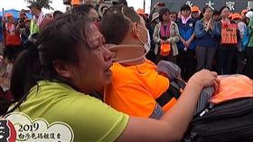 ▲信眾推著車禍癱瘓的兒子「鑽轎底」，祈求白沙屯媽祖進香保佑早日康復