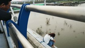 ▲女子抱腿坐在橋邊。（圖／都市快報）
