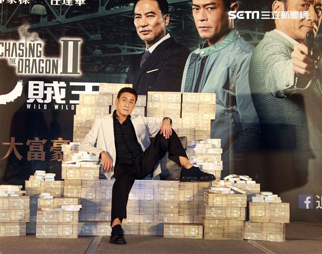 梁家輝出席電影「追龍II賊王」記者會，霸氣帥坐在鈔票椅瀟灑狂噴鈔票，展現史上最強悍匪氣魂。（記者邱榮吉/攝影）