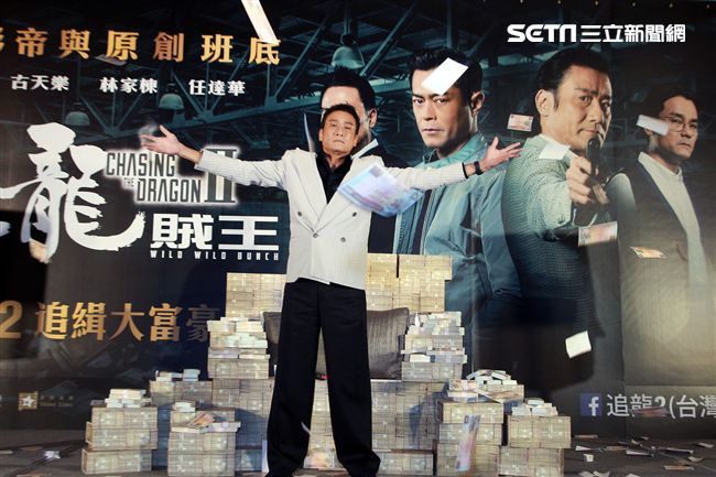 梁家輝出席電影「追龍II賊王」記者會，霸氣帥坐在鈔票椅瀟灑狂噴鈔票，展現史上最強悍匪氣魂。（記者邱榮吉/攝影）