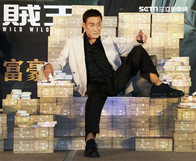 梁家輝出席電影「追龍II賊王」記者會，霸氣帥坐在鈔票椅瀟灑狂噴鈔票，展現史上最強悍匪氣魂。（記者邱榮吉/攝影）