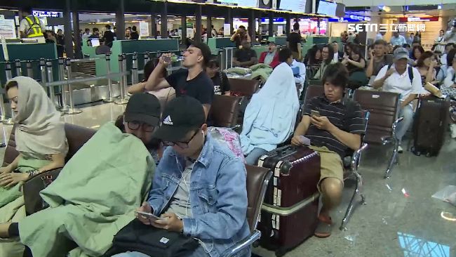 等機位！旅客蓋棉被睡機場　3C解悶