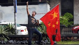 中國領事館前抗議　菲異議人士焚燒五星旗菲律賓資深記者卡波奈（Waldy Carbonell）1日前往中國領事館前，冒雨焚燒、撕裂中國五星國旗，並朝領事館比中指，對中國入侵領海表達不滿；下方安全島被寫上：「菲律賓是非賣品」。中央社記者陳妍君馬尼拉攝　108年7月1日