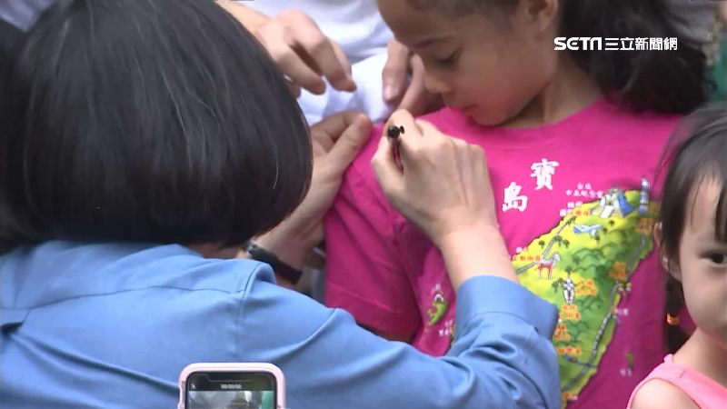 蔡英文蹲下來詢問小女孩是否同意，直到女孩點頭才簽名。（圖／資料照）