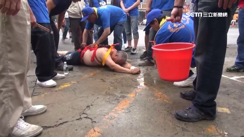 信眾灑水幫開路　乩身扭動如魚游進廟
