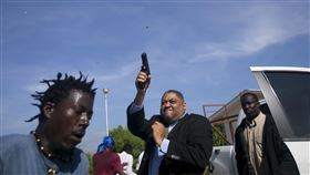 有數名抗議民眾猛拉海地參議員費提耶（Jean Marie Ralph Fethiere）的車門，怒氣沖沖地向他吼叫後，他直接走下車連開好幾槍，嚇得現場民眾驚慌失措，四處竄逃。（圖／美聯社／達志影像）