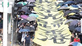 禁蒙面法首日　港人仍戴口罩遊行5日是香港實施禁蒙面法的第一天，但是許多港人仍然戴著口罩遊行抗議。圖為遊行隊伍下午3時許抵達灣仔，龍頭手持「我願榮光歸香港」的布條。中央社記者張謙香港攝　108年10月5日