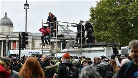 「反抗滅絕」發起全球抗議運動，要求各國政府減少碳排量，展開為期兩週的全球示威活動。圖為7日英國倫敦示威者爬上鐵架遭警方驅離。（圖／中央社／法新社提供）