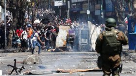 智利政府6日調漲地鐵票價，引發中學和大學生率先發難抗議，後來演變成反政府示威，表達對於總統皮涅拉和軍方的不滿。圖為21日民眾聚集於路障後方，與安全部隊發生衝突。（路透社提供）