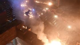 數十名防暴警察凌晨約5時30分從暢運道搶占理工大學大門處，校內示威者向警察丟擲多枚汽油彈並引燃路障，還有人從A座樓層平台丟擲汽油彈，現場一片火海。（法新社提供）