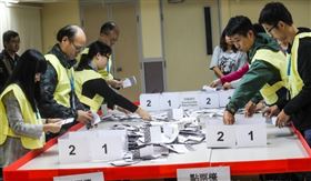 香港近日抗爭情勢逐漸趨緩，24日區議會選舉如期舉行，晚間10時30分結束投票後進行點票作業，灣仔一家投票站工作人員25日凌晨仔細清點選票。