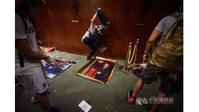 香港政府3月31日提出逃犯條例修訂草案，6月9日爆發反送中運動，反對逃犯條例修訂的民眾發起抗爭。圖為示威者7月1日衝進立法會會議廳，拆下並腳踹歷任立法會議員的肖像照。（中央社檔案照片）