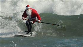 耶老衝浪活動邁入第10屆，800多名耶誕老人放下雪橇，拿起衝浪板在美國佛羅里達州海灘衝浪，募善款做公益。（圖取自facebook.com/SurfingSantas）