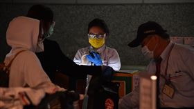 防疫專車載旅客　工作人員全副武裝受到武漢肺炎疫情影響，桃園國際機場22日不少旅客返台，由於防疫專車工作人員會與旅客近距離接觸，因此全程配戴護目鏡、手套與口罩避免飛沫感染。中央社記者林俊耀攝  109年3月22日