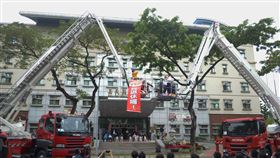 嘉義縣新舊雲梯車空中交接嘉義縣消防局23日舉行「30公尺雲梯車及消防空拍機等新式救災器材啟用儀式」，車齡20年的雲梯車垂掛「我退休囉！」布條，與新式電腦操控雲梯車進行空中交接。中央社記者蔡智明攝　109年4月23日