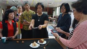 手機攝影達人周麗紅返鄉授課（3）金門縣古寧頭社區發展協會22日邀請手機攝影達人周麗紅（右3）授課，指導學員靜物拍攝技巧，周麗紅說，只拍一個蛋糕顯得單調，她隨手擺上幾片枯葉，再放上枯枝，整個畫面立時豐富不少。中央社記者黃慧敏攝　109年5月22日