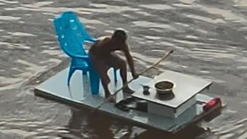 不懼洪災！男坐木板江上漂　愜意喝茶