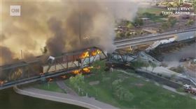 美國亞利桑那州29日清晨發生火車出軌事故，一列貨運列車在坦佩鎮湖橋樑上出軌，列車全面燃燒引發巨大火勢與濃煙，現場近百位消防員投入控制火勢。（圖取自CNN網頁cnn.com）