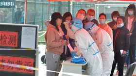 據官方通報，中國29日新增武漢肺炎確診病例25例，其中境外移入24例，本土1例是山東省青島市一名女護士，是在隔離醫院內遭到感染。圖為12日青島民眾排隊進行核酸檢測。（圖／中新社）
