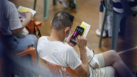 打疫苗不忘看盤  民眾緊盯台股台北市幼兒園、安親班教職員7日起施打莫德納疫苗，民眾接種後到留觀區稍作休息，拿出手機關注台股。中央社記者鄭清元攝  110年7月7日